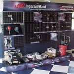 Ingersoll Rand display showcasing power tools, compressors, and accessories, neatly arranged on a grid-style stand with promotional branding.